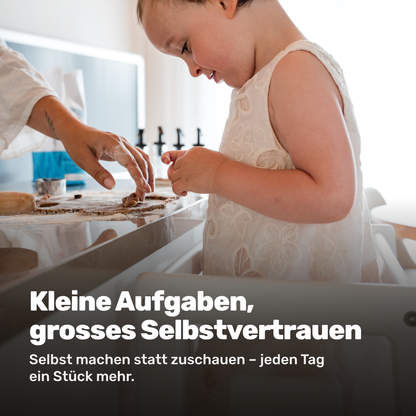 Kind backt selbststaendig im Tuki Lernturm auf Augenhoehe mit den Eltern