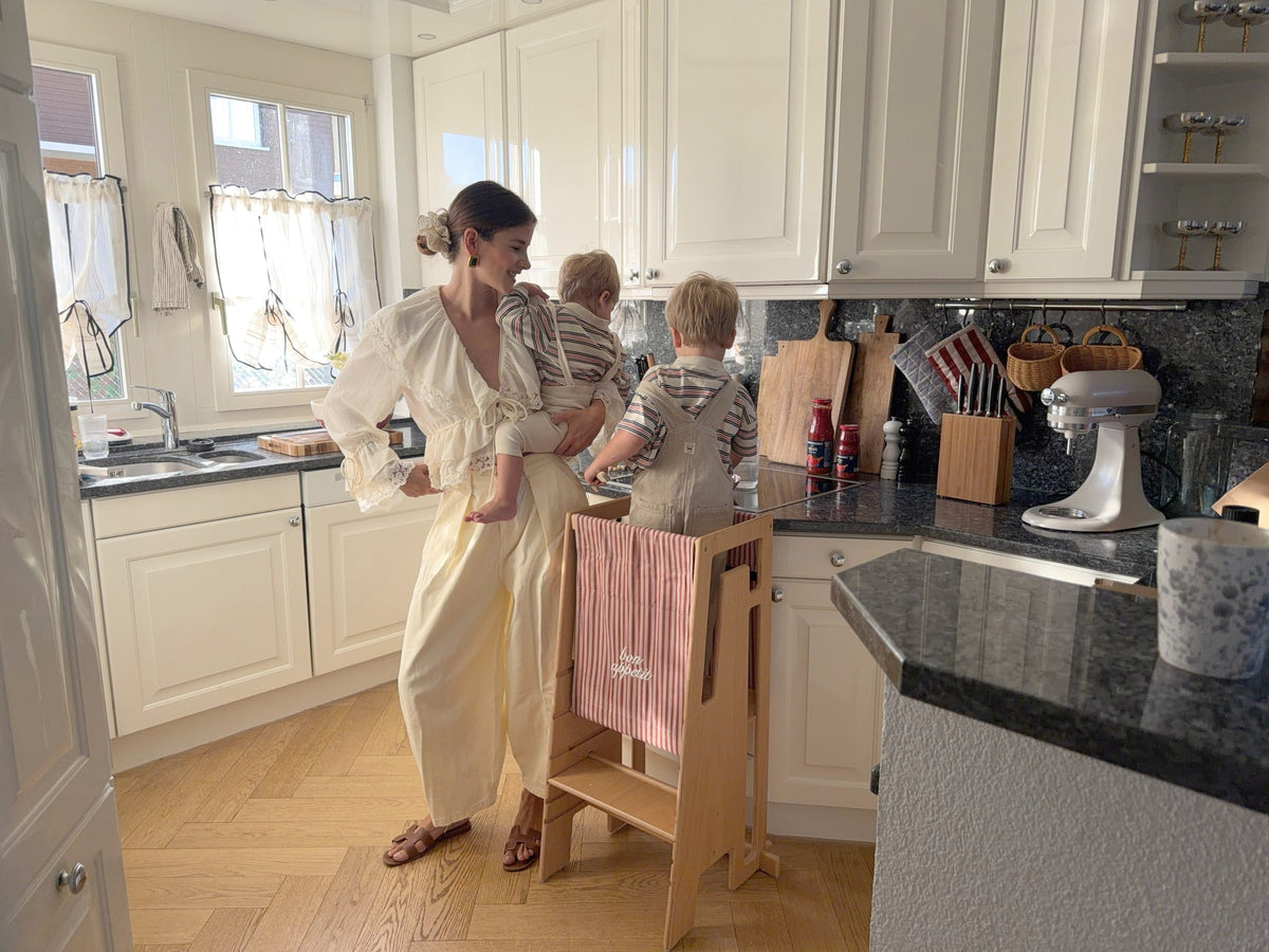 Michèle Krüsi kocht mit ihren Kindern, eines steht im Tuki Lernturm mit Startertuch «bon appétit»